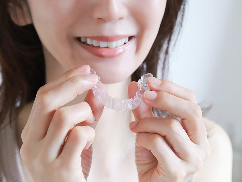 マウスピース型のホームホワイトニングを手に持つ女性